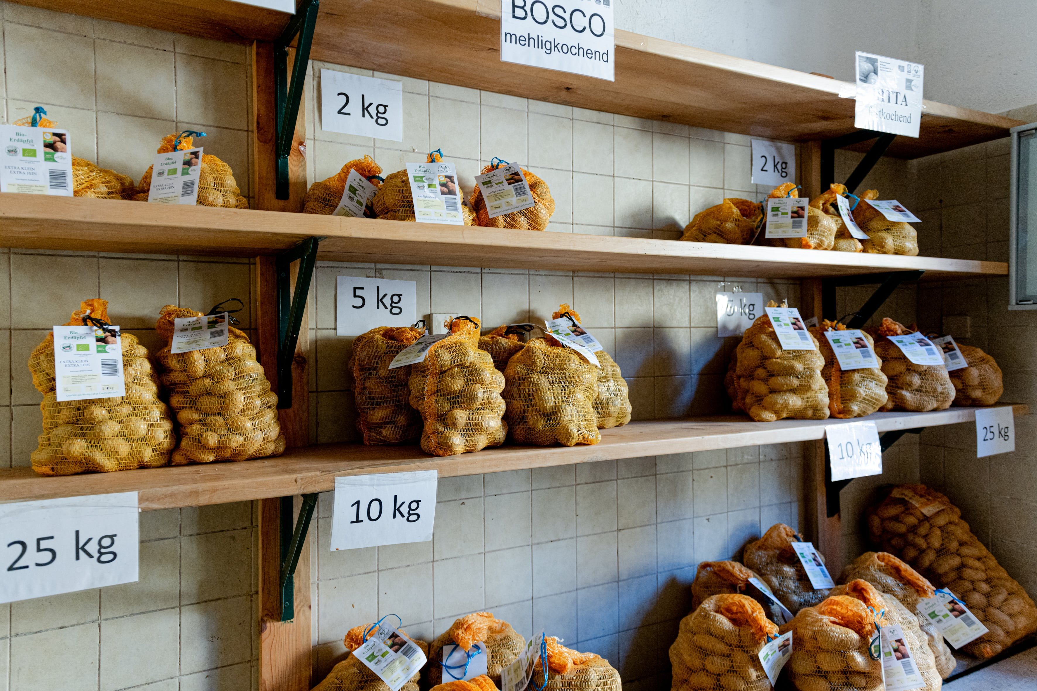 Prodejní místnost s regály s pytli na brambory v různých hmotnostních jednotkách.