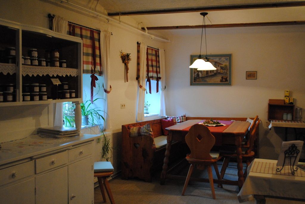 Útulná kuchyně s dřevěným nábytkem a kostkovanými závěsy.