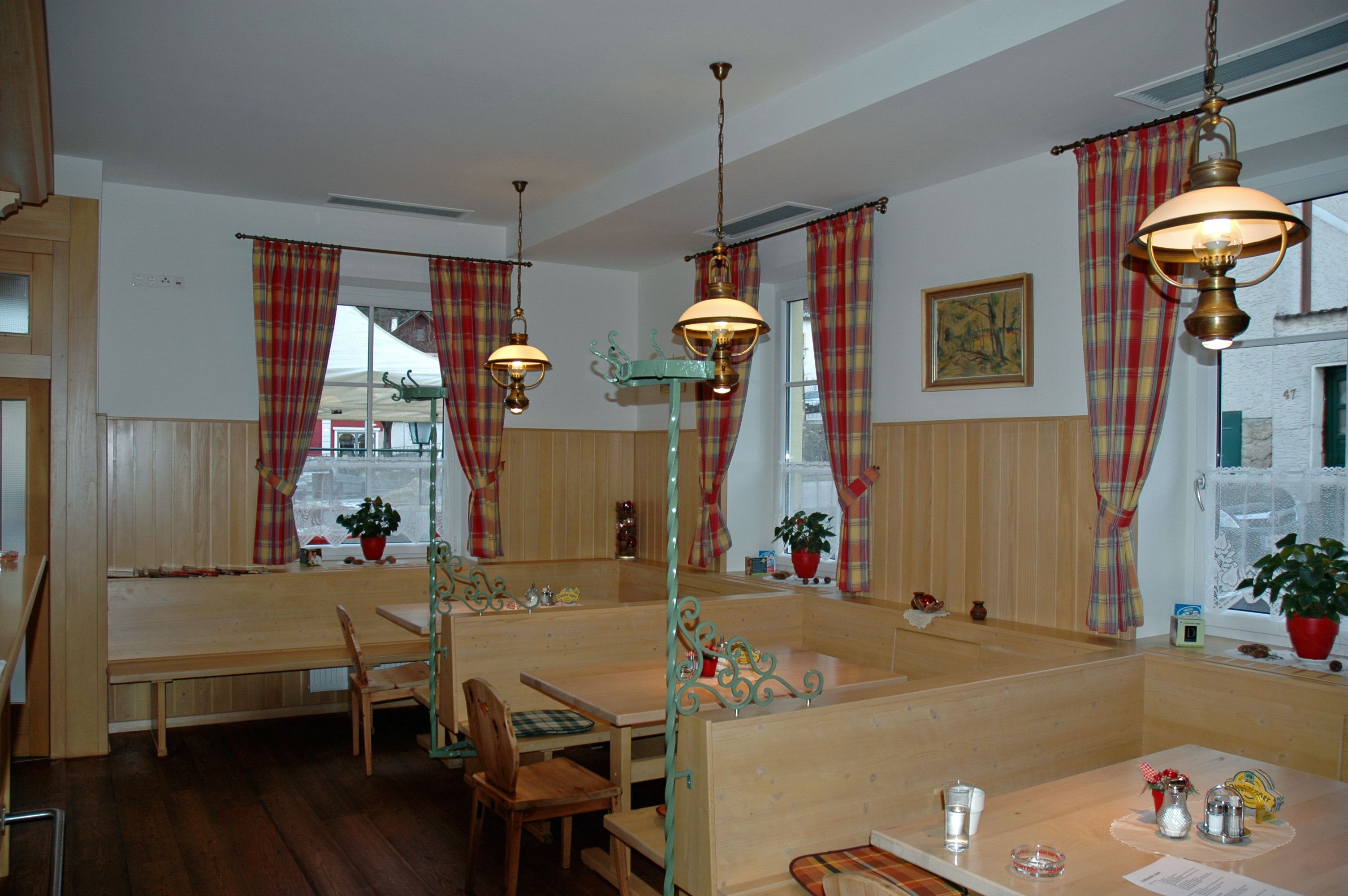 Útulná jídelna s dřevěným nábytkem a kostkovanými závěsy.