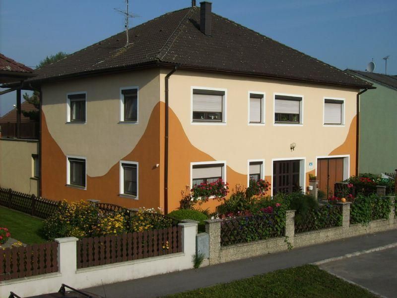 Dvoupodlažní dům s oranžovo-béžovou fasádou a zahradou.