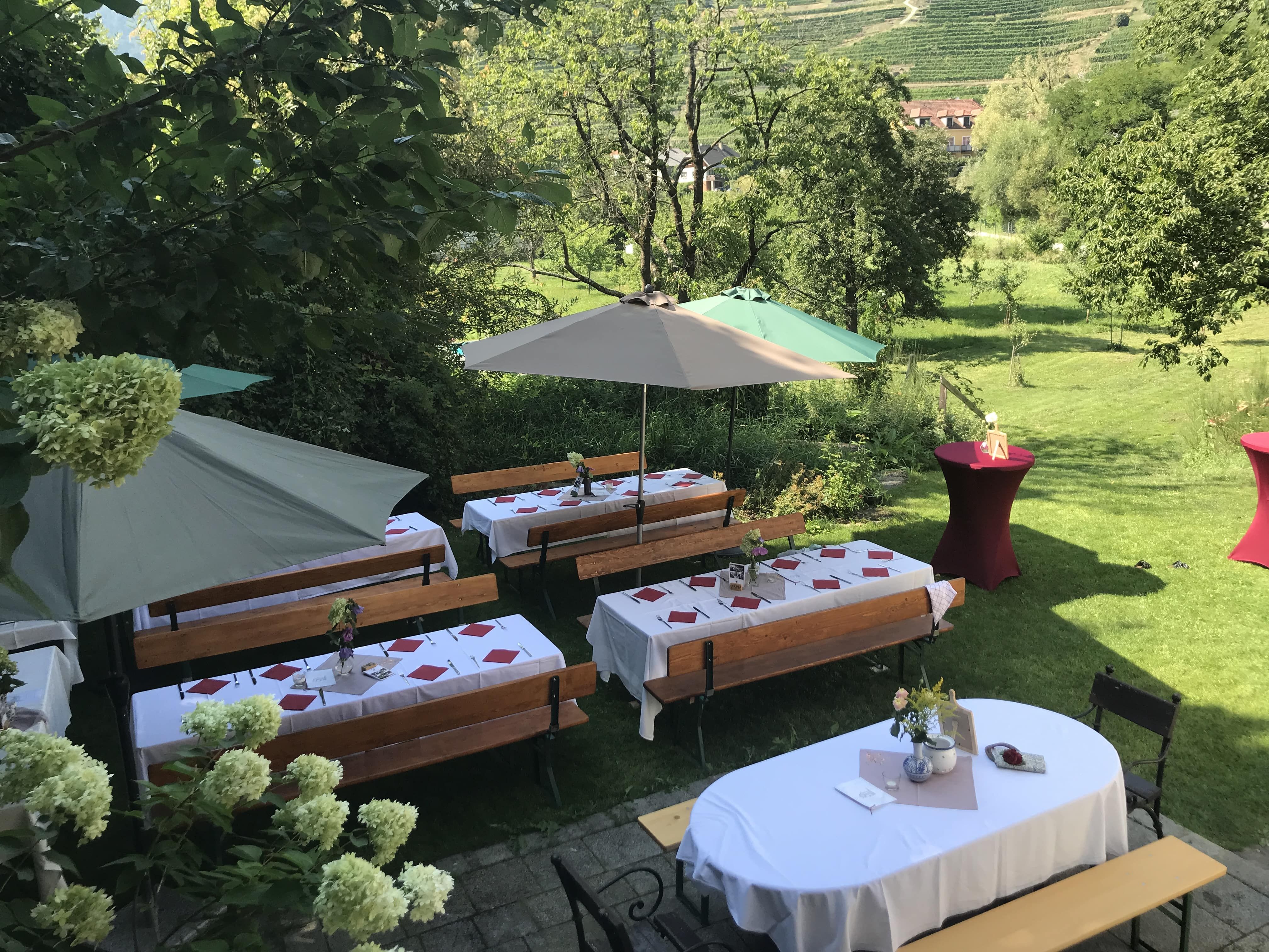 Slavnostně prostřené venkovní stoly se slunečníky a květinovou výzdobou.