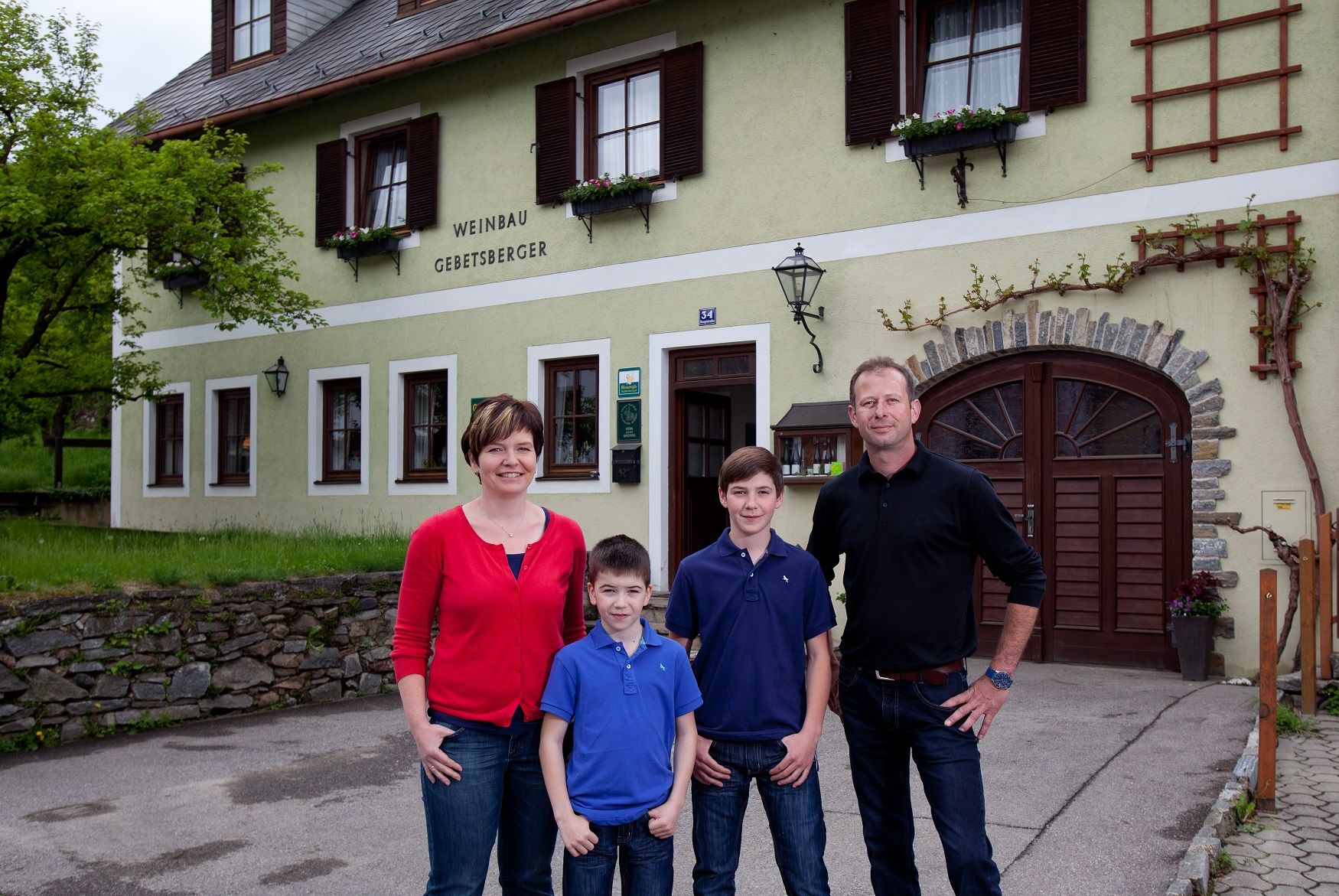 Rodina stojí před budovou s nápisem "Weinbau Gebetsberger".