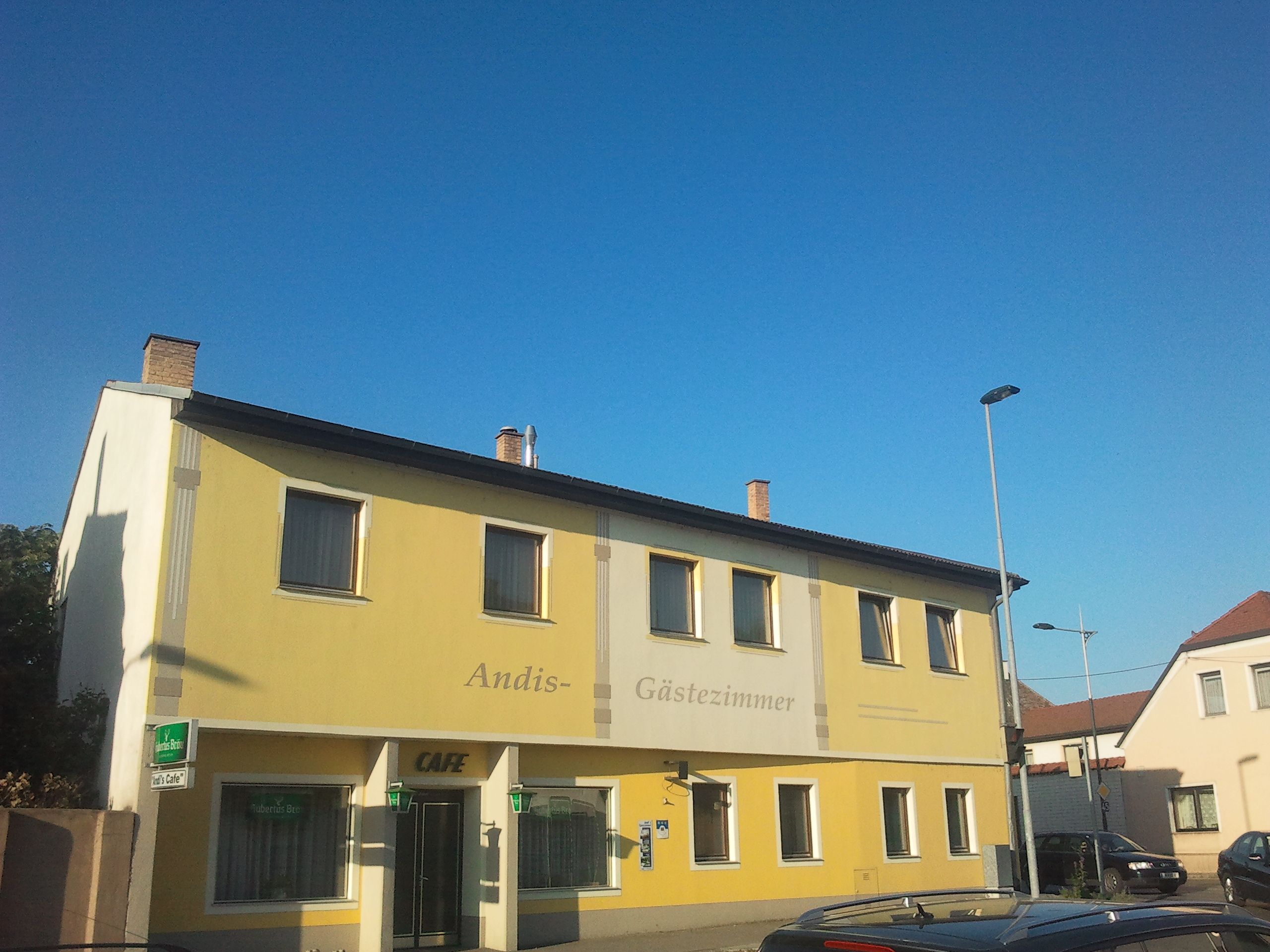 Žlutá budova s označením "Andis Gästezimmer" a "Cafe".