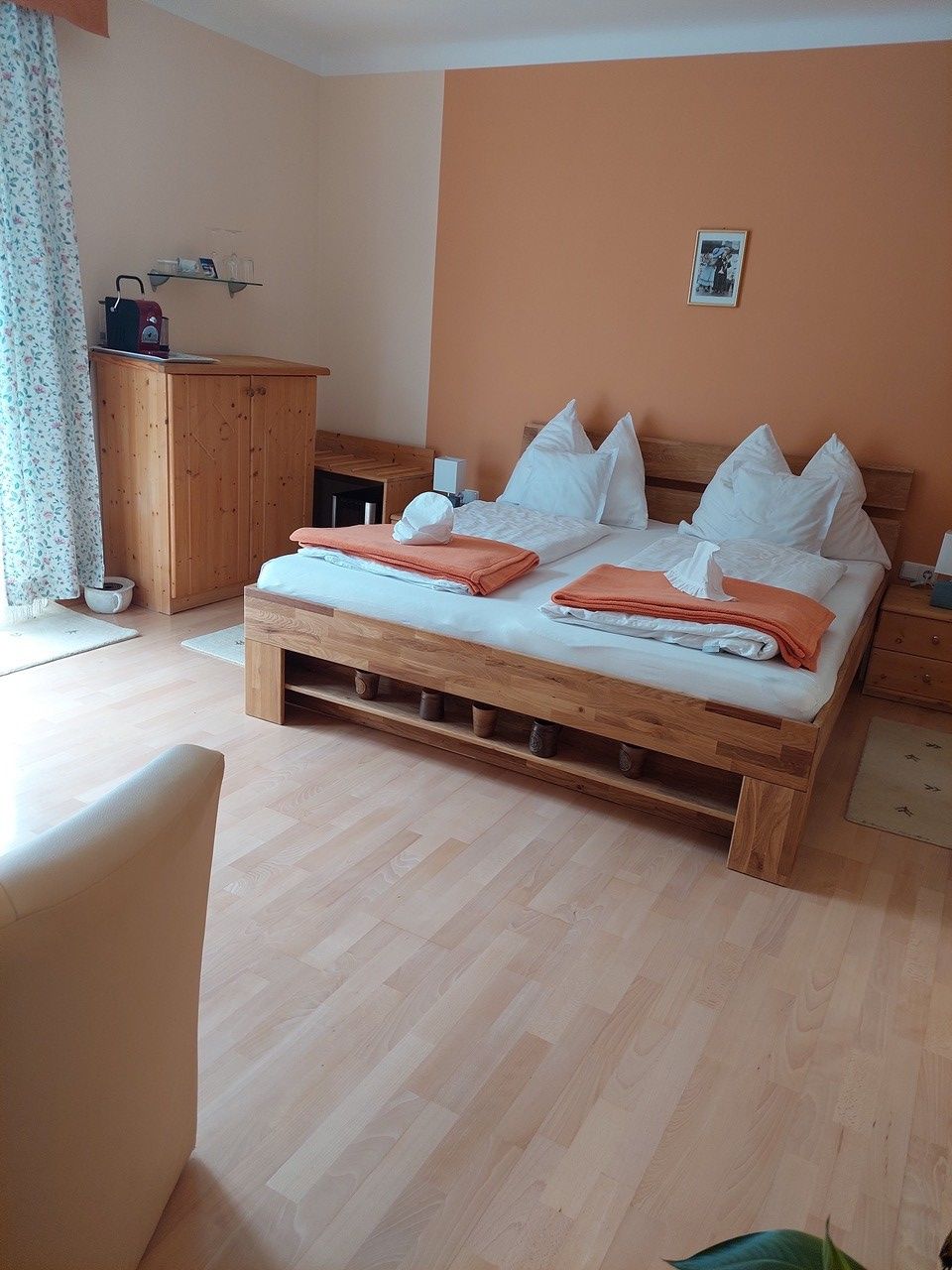 Útulná ložnice s manželskou postelí, dřevěným nábytkem a oranžovou stěnou.