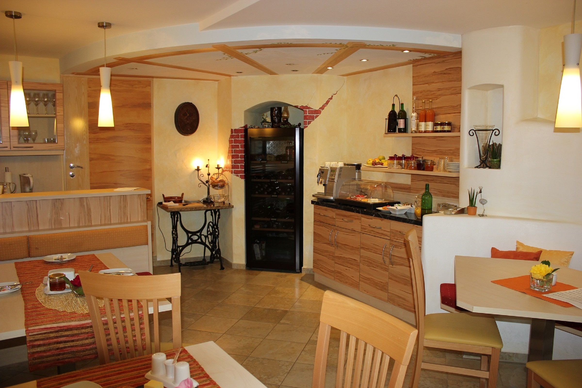 Útulná snídaňová místnost s dřevěným nábytkem, prostřenými stoly a bufetem s nápoji a jídlem.