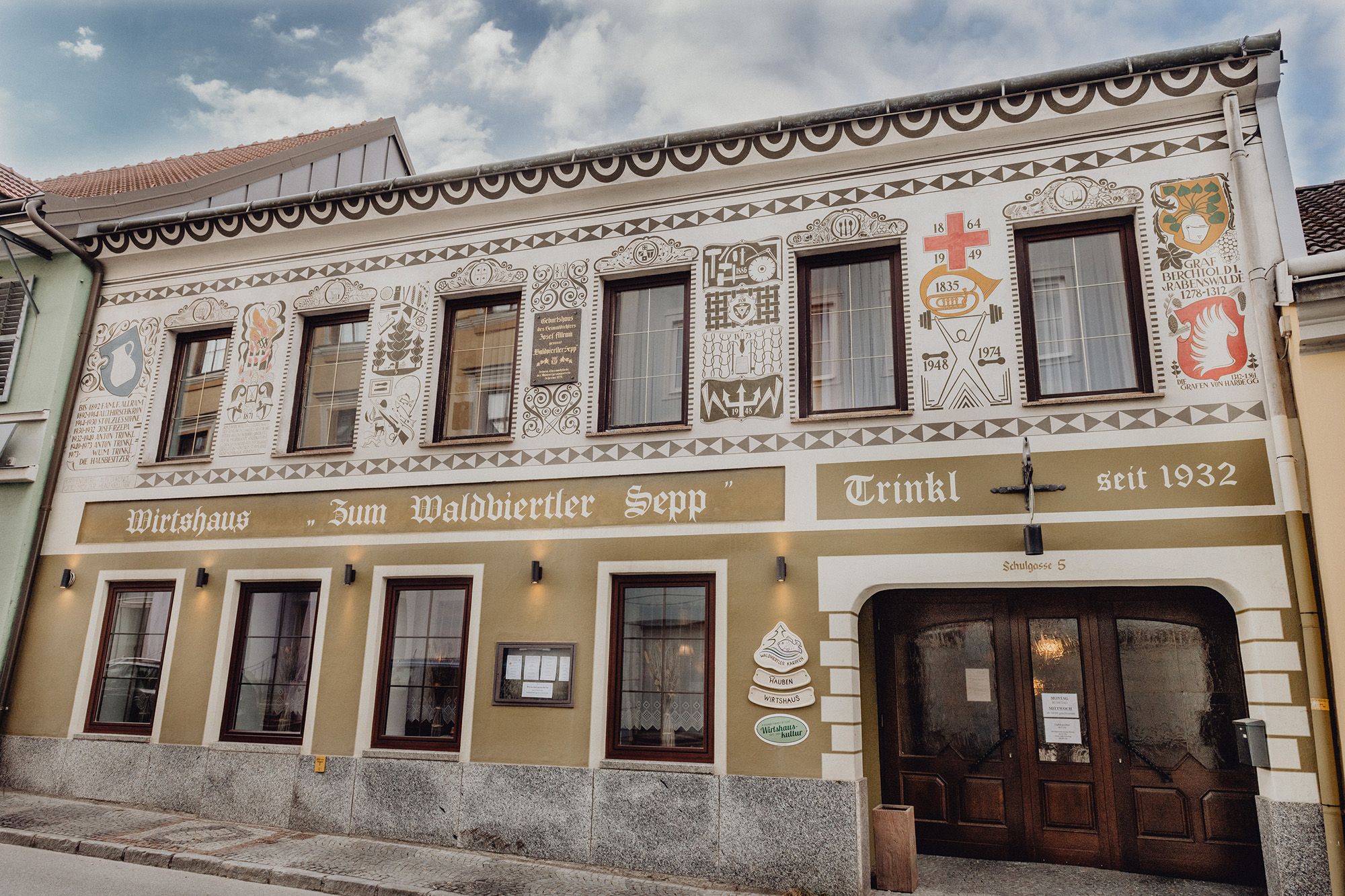 Fasáda tradičního hostince s dekorativními malbami a nápisem "Zum Waldviertler Sepp" ve Schremsu.