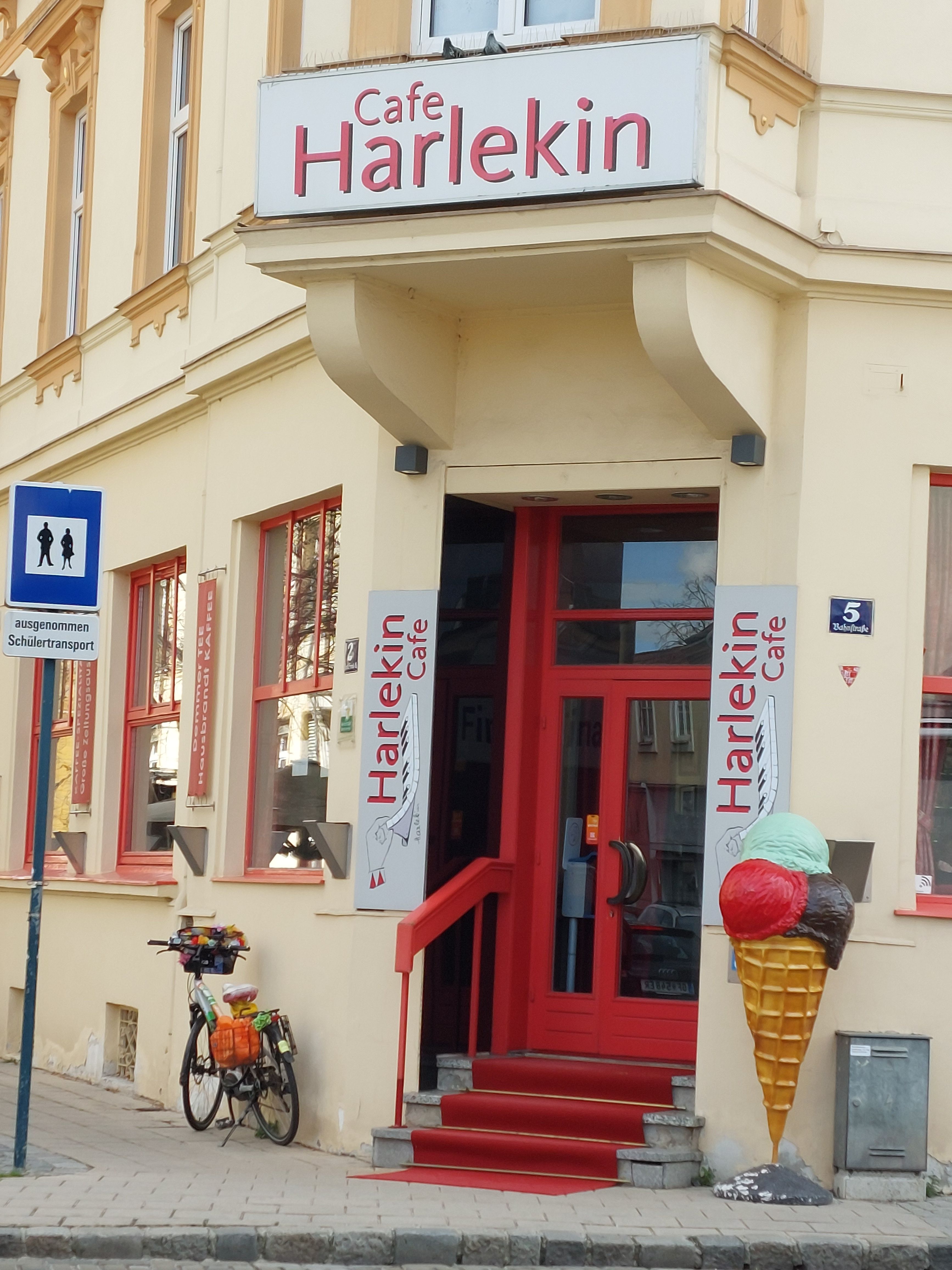 Vchod do kavárny Harlekin s červenými dveřmi a dekorací zmrzlinového kornoutu.