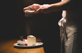 Talířek se šlehačkou a malinovým sorbetem, posypaný moučkovým cukrem.