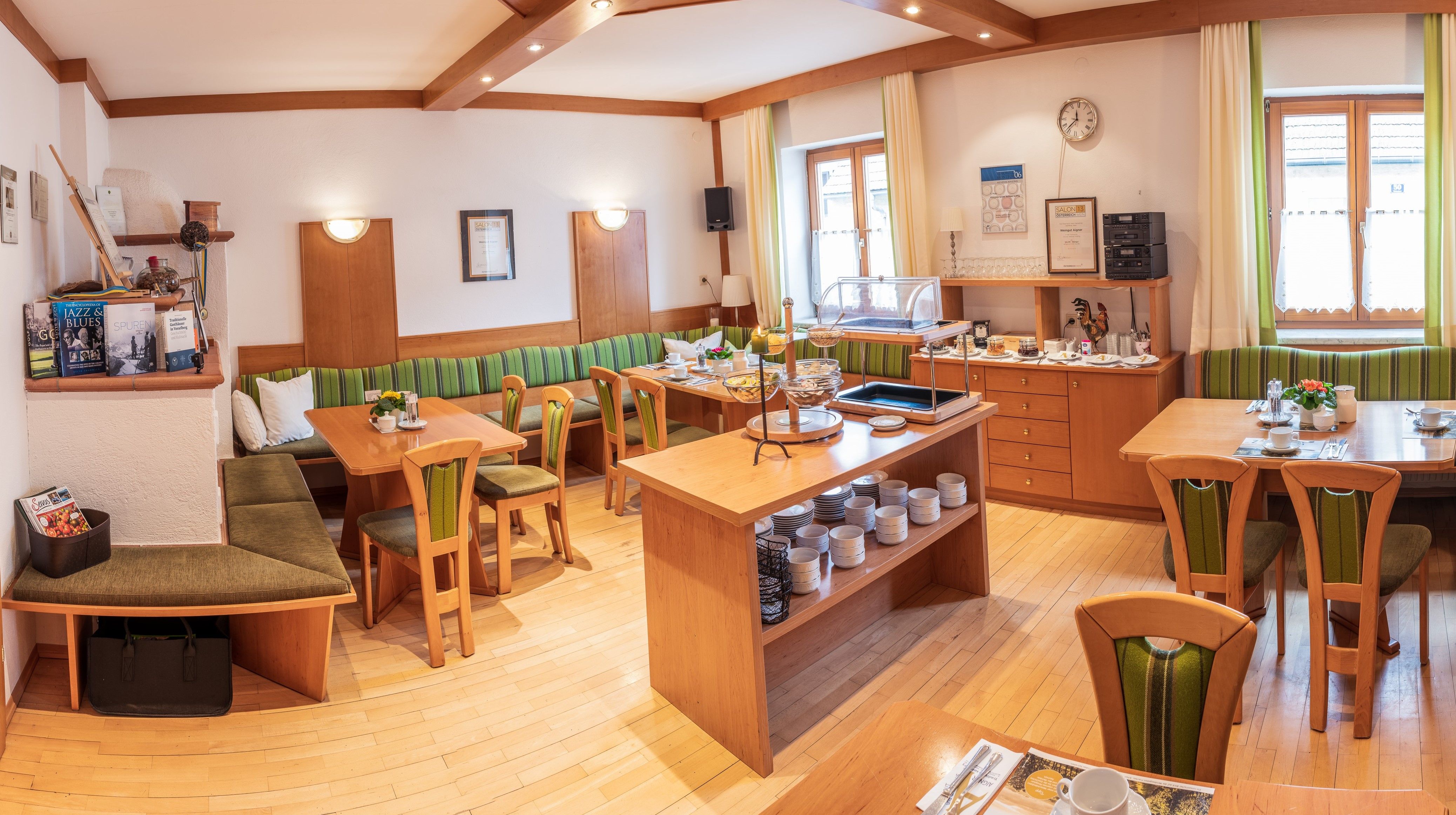 Útulná snídaňová místnost s dřevěným nábytkem, prostřenými stoly a bufetem.