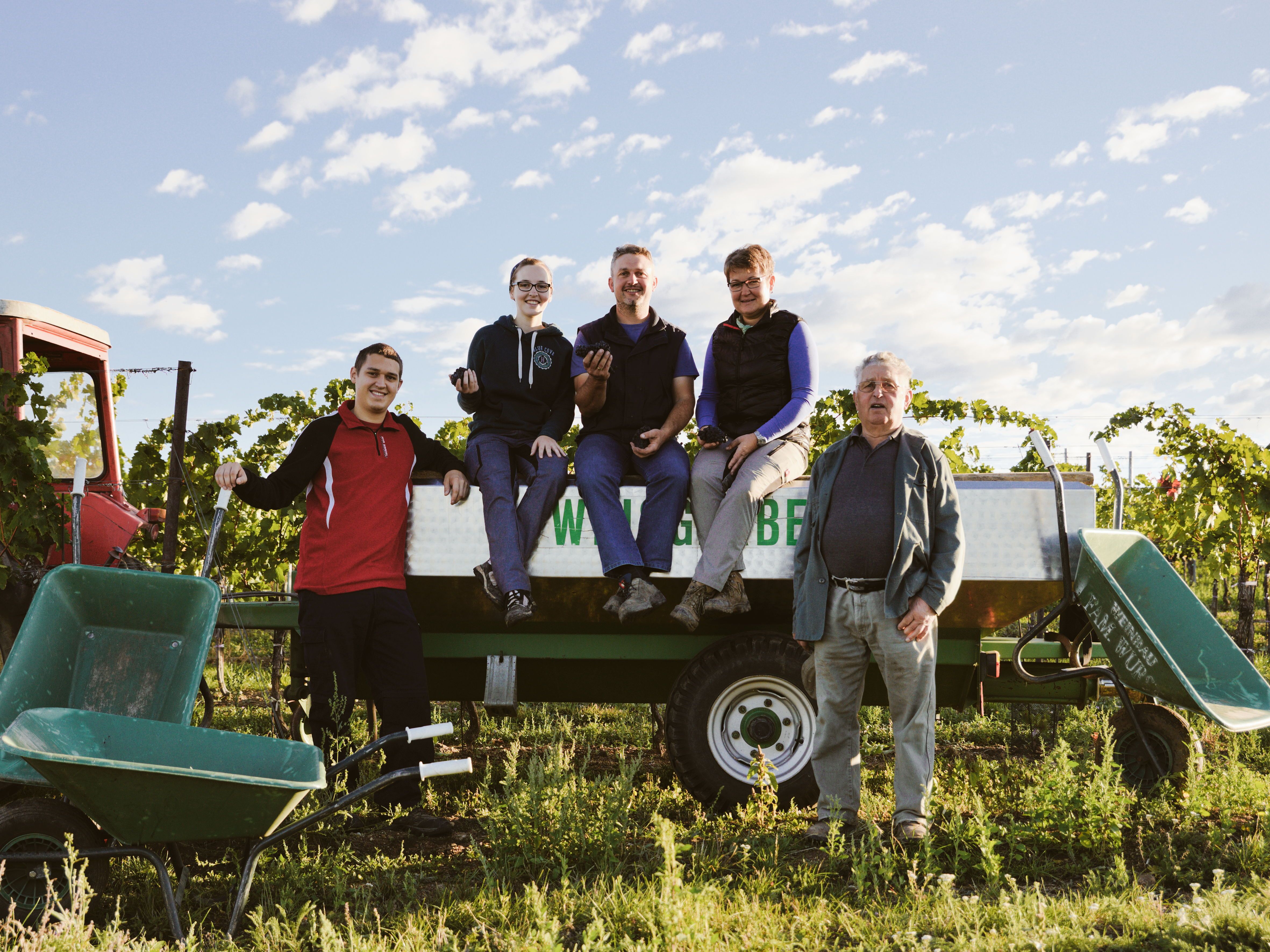 Rodina pózuje na přívěsu traktoru na vinici.